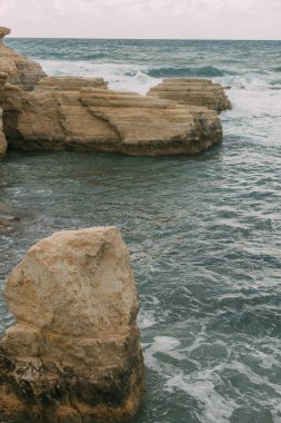 Akdeniz sularında kayaların yanında beyaz köpük. 