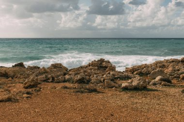 sunlight on rocks near mediterranean sea against sky with white clouds  clipart