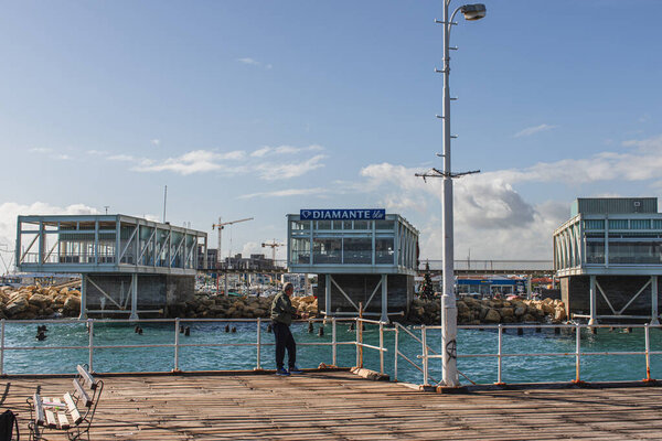 PAPHOS, CYPRUS - MARCH 31, 2020: man standing in near sea in harbor 