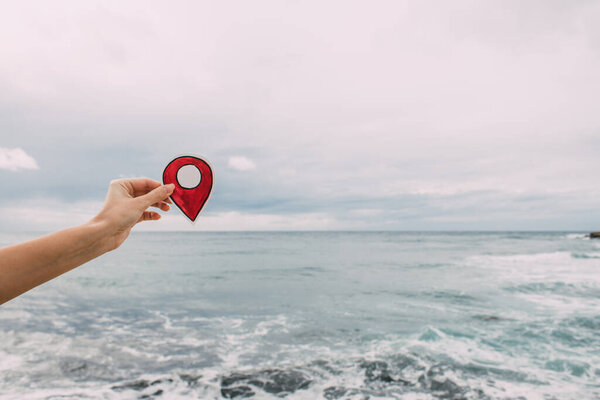 cropped view of woman holding paper as location sign near mediterranean sea