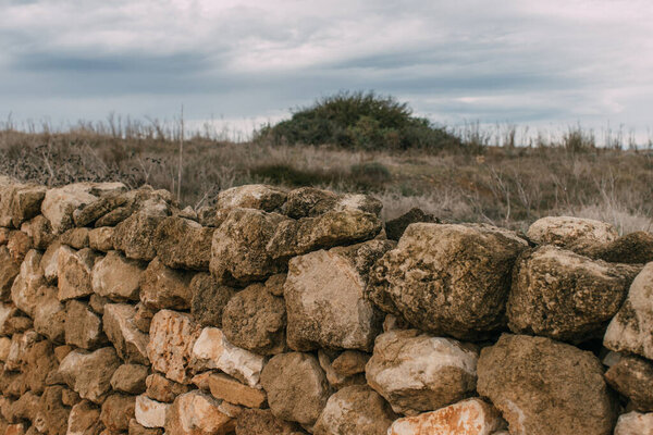 wall with stones near lawn against sky with clouds 