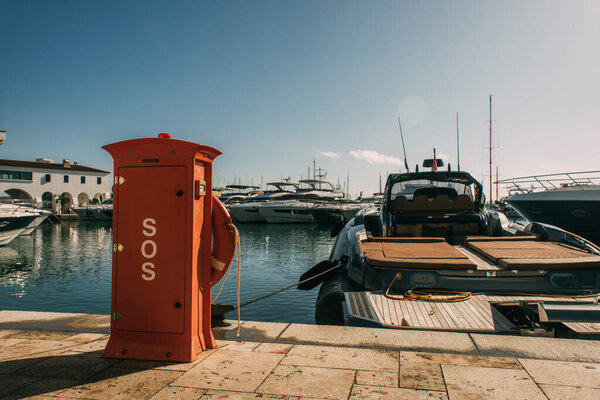 red booth with sos lettering near yachts in mediterranean sea