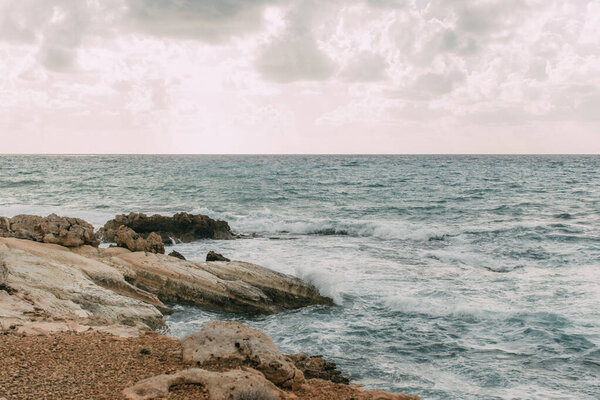 coastline with stones near mediterranean sea against sky with clouds 