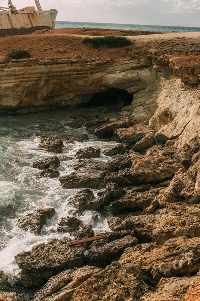 wet rocks near mediterranean sea against sky with white clouds 