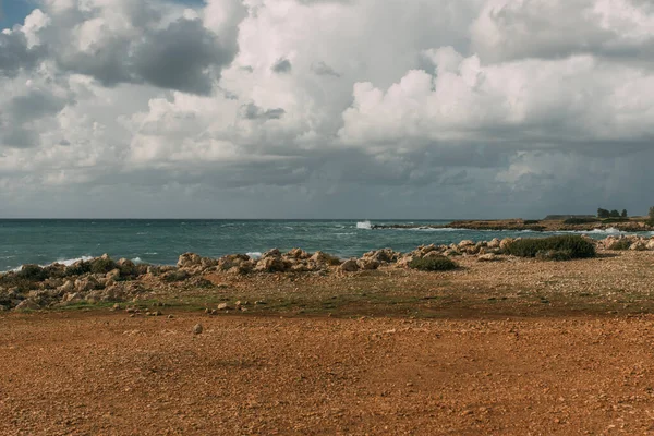 rocks near mediterranean sea against sky with white clouds 
