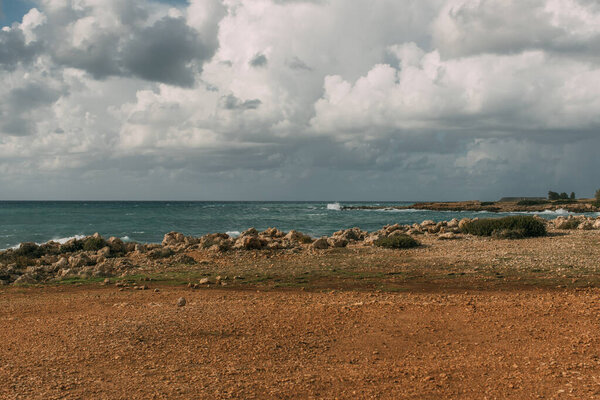 rocks near mediterranean sea against sky with white clouds 