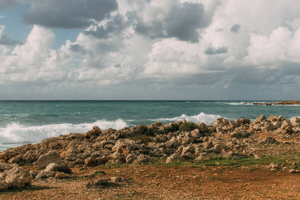 sunshine on rocks near mediterranean sea against sky with white clouds 