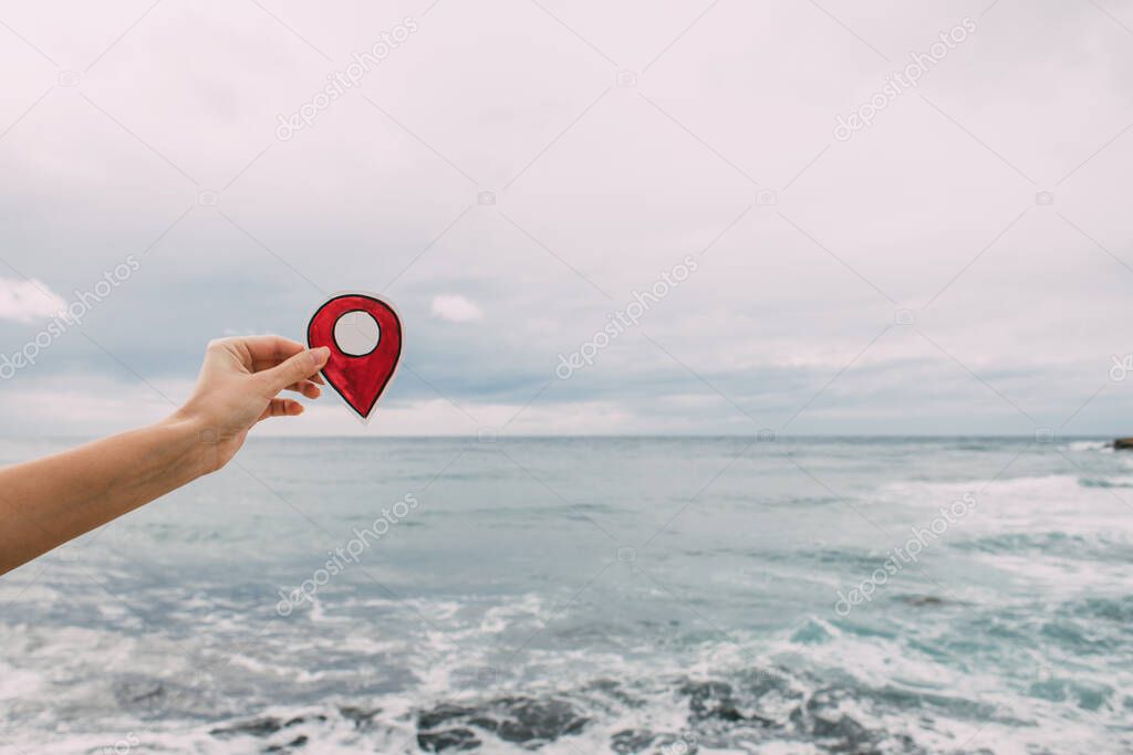 cropped view of woman holding paper as location sign near mediterranean sea