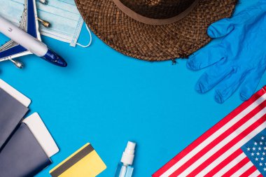 Amerikan bayrağı ve tıbbi maske yakınındaki oyuncak uçak yakınlarındaki pasaportların mavi arka planda üst görüntüsü