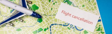 Top view of card with flight cancellation near toy plane on map isolated on blue, panoramic shot clipart