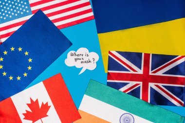 Top view of speech bubble with where is your mask lettering near flags of countries isolated on blue  clipart