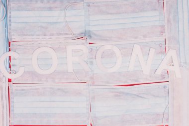 Kırmızı arka planda tıbbi maskelerde Corona harflerinin üst görüntüsü