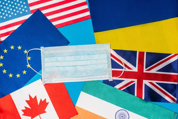 Widok Góry Maskę Medyczną Flagach Krajów Odizolowanych Niebiesko — Zdjęcie stockowe