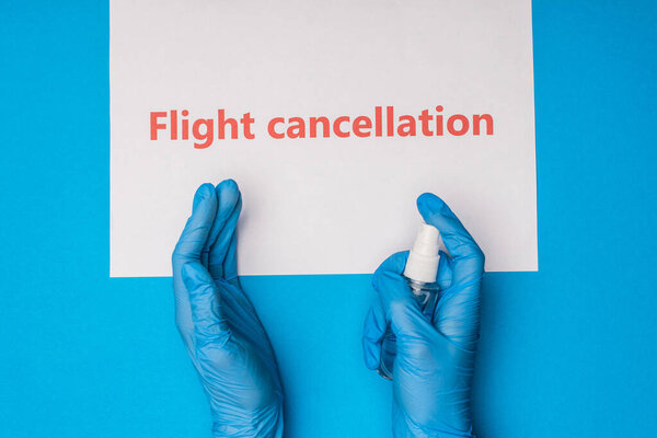 Вид сверху врача, держащего в руках бутылку шампанского рядом с картой с отметкой об отмене рейса на синем фоне
