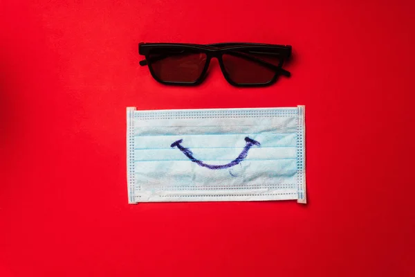 赤い背景に笑顔とサングラスを持つ医療用マスクのトップビュー — ストック写真