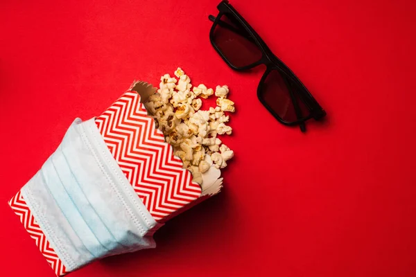 Top View Medical Mask Bucket Popcorn Sunglasses Red Background — Stock Photo, Image