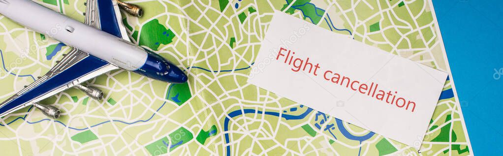 Top view of card with flight cancellation near toy plane on map isolated on blue, panoramic shot