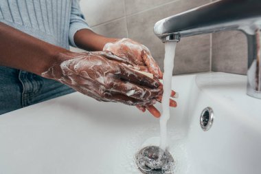 Afro-Amerikan kadının sabunla ellerini yıkaması.