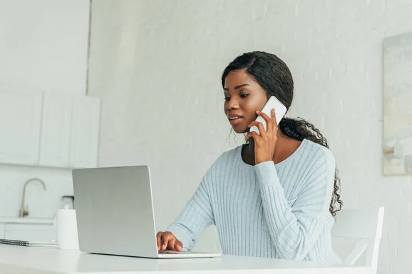 Freelancer Afroamericano Concentrado Hablando Smartphone Mientras Usa Portátil Casa —  Fotos de Stock