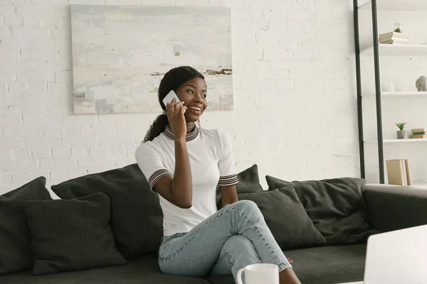 Cheerful African American Girl Sitting Sofa Talking Smartphone Looking Away — Stock Photo, Image