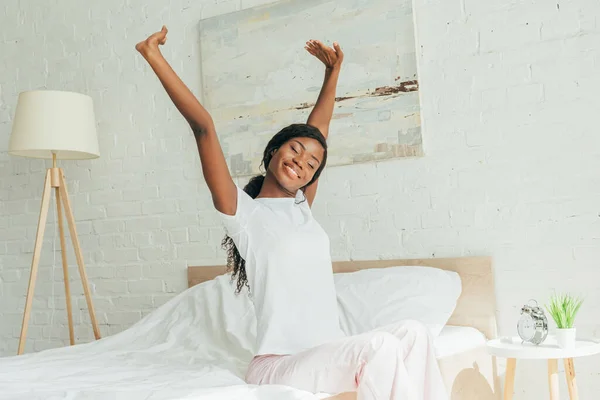 Sorrindo Menina Americana Africana Pijama Sentado Cama Com Olhos Fechados — Fotografia de Stock