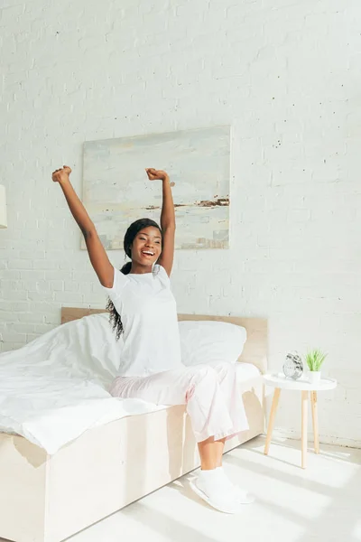 Happy African American Girl Pajamas Stretching Raised Hands While Sitting — Stock Photo, Image