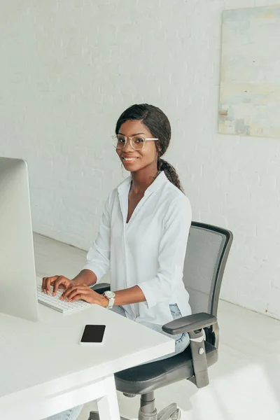 Feliz Afroamericano Freelancer Escribiendo Teclado Mientras Sonríe Cámara —  Fotos de Stock