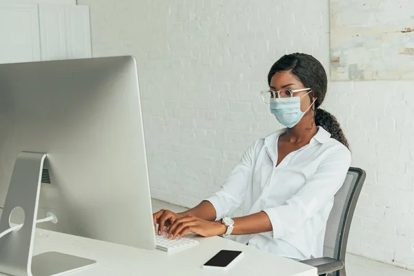 Attento Freelance Afroamericano Maschera Medica Digitando Sulla Tastiera Vicino Monitor — Foto Stock