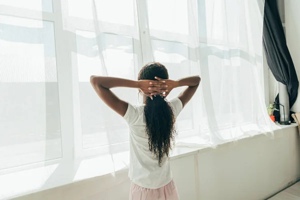 Back View African American Girl Standing Window Sunshine Hands Head — Stock Photo, Image