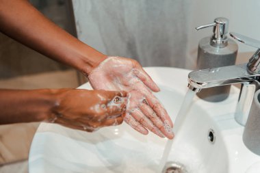 Afro-Amerikan kadının banyoda sabunla ellerini yıkaması.