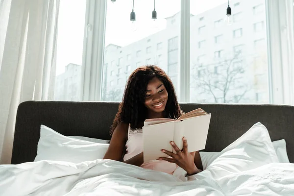 African American Woman Reading Book Smiling Bed Bedroom — Stock Photo, Image