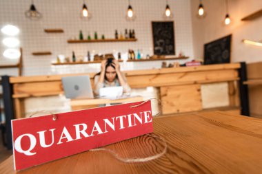 Altüst olmuş kafe sahibinin seçici odak noktası ve masada karantina yazıları olan kırmızı kart