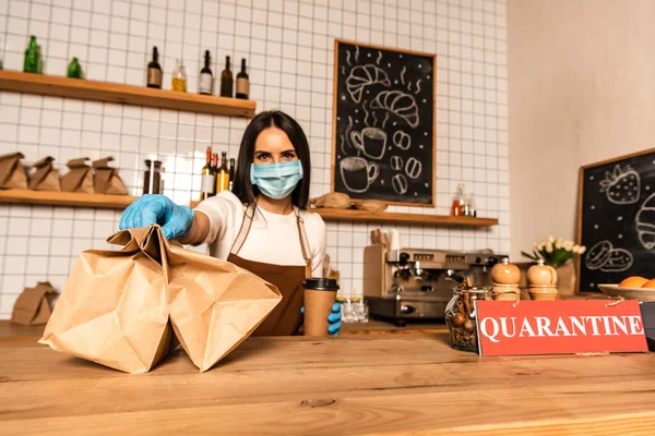 Cafébesitzer Medizinischer Maske Mit Einwegbecher Kaffee Zeigt Papiertüten Neben Tisch — Stockfoto