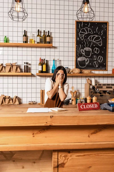 Cafébesitzer Deckt Gesicht Neben Tisch Mit Papieren Taschenrechner Karte Mit — Stockfoto