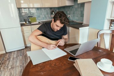 Bilgisayarın yanında oturan gitarlı genç adamın yüksek açılı görüntüsü