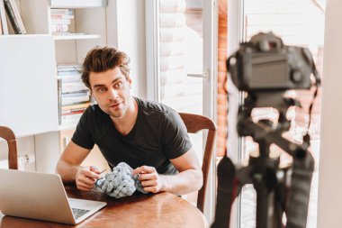 Dijital kameraya bakarken örgü ören genç vlogger 'ın seçici odağı