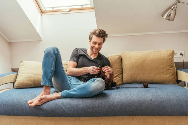 Jovem Feliz Tricô Enquanto Sentado Sofá Casa Sala Sótão — Fotografia de Stock