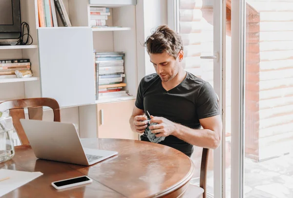 Hombre Joven Concentrado Tejiendo Mientras Está Sentado Cerca Computadora Portátil — Foto de Stock