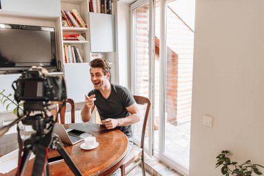 Tripoddaki dijital kamerayı işaret eden neşeli vlogger seçici odağı