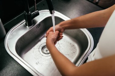 Karantina sırasında mutfakta lavaboda ellerini yıkayan kadın görüntüsü