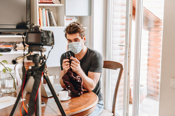 селективный фокус видеоблоггера в медицинской маске, дающего уроки вязания онлайн
