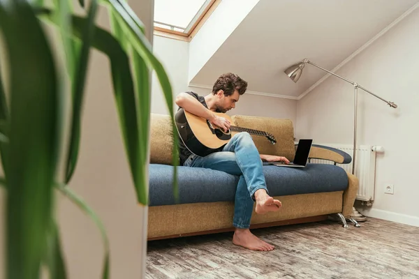 Genç Bir Adamın Gitar Çalarken Dizüstü Bilgisayarın Yanında Boş Ekranla — Stok fotoğraf