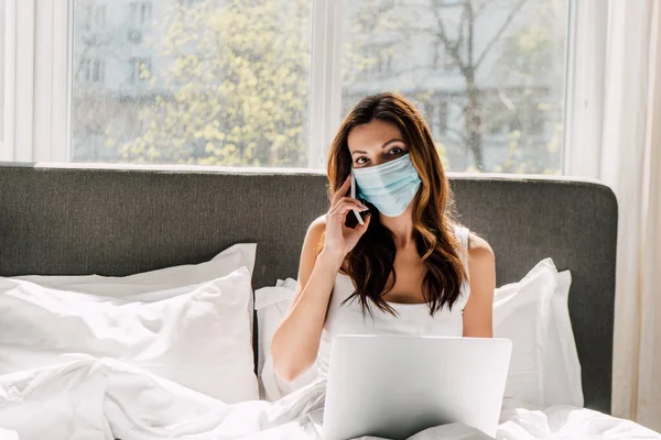 Kvinnlig Frilansare Medicinsk Mask Talar Smartphone Och Arbetar Laptop Självisolering — Stockfoto