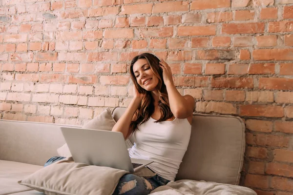 Chica Sonriente Escuchando Música Con Auriculares Portátil Sofá Durante Autoaislamiento —  Fotos de Stock