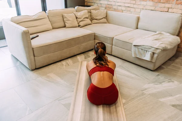 女孩在家里的瑜伽垫上舒展身体的背影 — 图库照片
