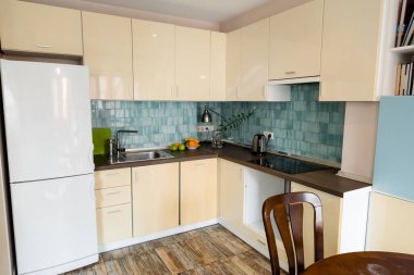 Modern mutfakta lavabo ve musluğun yanındaki modern buzdolabı. 
