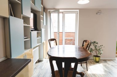 Ahşap sandalyeli modern yemek odası ve yeşil bitkinin yanındaki masa. 