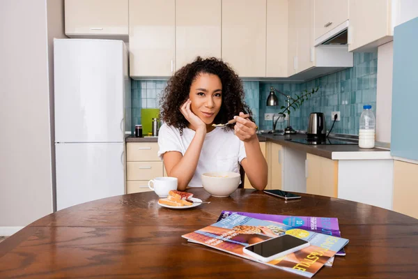 African American Woman Holding Spoon Corn Flakes Cup Coffee Smartphone — Stock Photo, Image