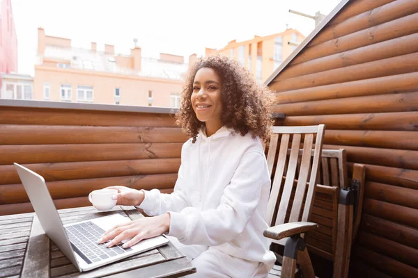 Happy African American Freelancer Holding Cup Using Laptop — Stock Photo, Image