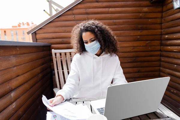 医療用マスクを着たアフリカ系アメリカ人の少女がノートパソコンの近くで — ストック写真